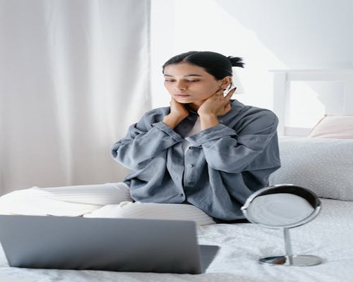A woman lightly massaging her neck while working